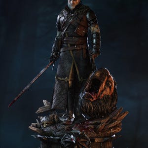May include: A detailed collectible figure of a white-haired warrior in dark leather and chainmail armour, holding a long sword. The figure stands on a base with a severed monster head, a helmet, and a wolf medallion, with the text TANUKI FIGURES.