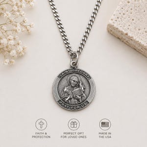 May include: A silver-toned metal Saint Gregory pendant necklace on a curb chain. The circular medal features a relief image of Saint Gregory holding a book and a quill, with the text SAINT GREGORY PRAY FOR US embossed along the outer border.