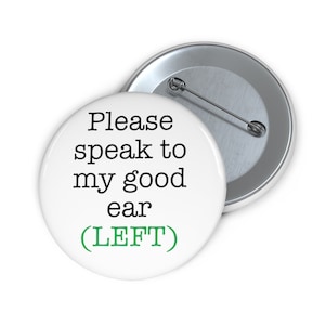 Op de afbeelding: Witte knop met zwarte tekst die "Praat alsjeblieft met mijn goede oor (LINKS)" in groene tekst zegt.