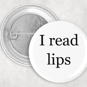 Puede incluir: Botón blanco con texto negro que dice "Leo los labios".