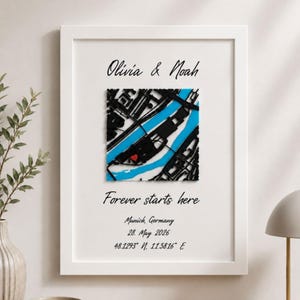 Può includere: Un quadro decorativo con i nomi Olivia & Noah, il testo Forever starts here, Munich, Germany, 28. May 2026 e le coordinate 48.1293 N, 11.5816 E. Una mappa quadrata centrale mostra strade nere, acqua blu e un piccolo cuore rosso.