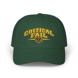 May include: A dark green baseball cap featuring the embroidered text CRITICAL FAIL in a yellow collegiate font. Below the text is a yellow graphic of a twenty-sided die with the number 1 centered, flanked by two horizontal yellow lines.
