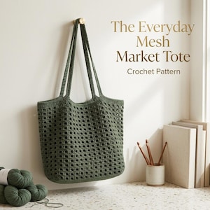 May include: An olive green crochet mesh market tote bag with two long shoulder straps hanging on a wall hook. The text The Everyday Mesh Market Tote Crochet Pattern is visible. A skein of green yarn and crochet hooks are nearby.