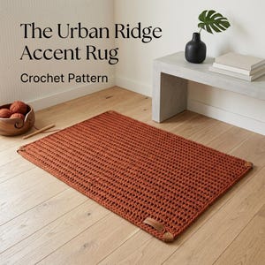 Peut inclure: Un tapis rectangulaire au crochet de couleur rouille avec un motif en grille texturé et de petits accents en cuir aux coins. Le texte The Urban Ridge Accent Rug Crochet Pattern est visible en haut à gauche au-dessus du tapis sur le sol.