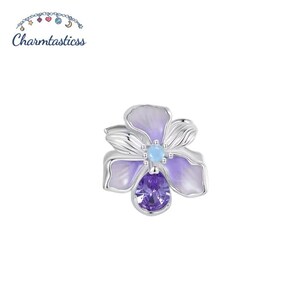 Pode incluir: Um berloque de flor em tom prateado com pétalas em camadas em esmalte violeta claro e branco. O centro da flor é acentuado com uma pequena pedra redonda azul-clara e um único cristal facetado em forma de gota na cor violeta escuro.