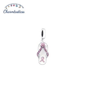Könnte beinhalten: Ein silberfarbener Anhänger in Form einer Flip-Flop-Sandale, verziert mit einer Reihe kleiner rosa Kristalle an den Riemen und einem rosa Schleifenemblem in der Mitte der Sohle. Der Anhänger hat eine runde Öse zur Befestigung an einem Armband.