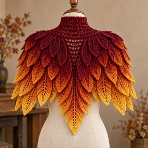 Könnte beinhalten: Ein gehäkeltes Capelet mit hohem Kragen und einem geschichteten Design aus blattförmigen Motiven. Das Kleidungsstück zeigt einen Farbverlauf, der am Kragen in Dunkelrot beginnt und zu den unteren Rändern hin in ein helles Gelb übergeht.