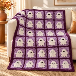 May include: A crochet blanket featuring a grid of square patches, each displaying a white ghost with black eyes on a purple background. The blanket is constructed from alternating shades of light and dark purple yarn squares.