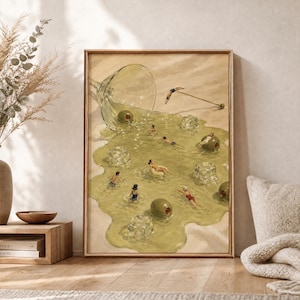 May include: A framed wall art print depicting a spilled martini glass on a sandy surface. The spilled liquid forms a pool where small figures swim among large green olives and clear ice cubes. A cocktail pick rests on the sand nearby.