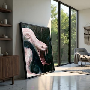 Könnte beinhalten: Ein gerahmter Wandkunstdruck, der eine blassrosa Schlange mit weit geöffnetem Maul zeigt, die scharfe Reißzähne und eine lange Zunge vor einem dunklen, strukturierten Hintergrund offenbart. Das Kunstwerk ist in einem schwarzen Rahmen präsentiert.