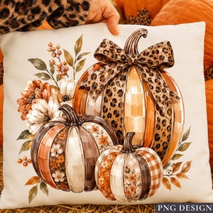 May include: A square throw pillow featuring a printed illustration of three pumpkins. The largest pumpkin is topped with a leopard print bow. The pumpkins are decorated with floral patterns, plaid, and leopard print, surrounded by autumn leaves.