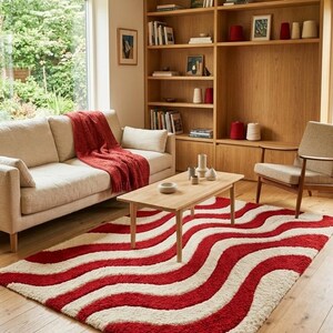 May include: A rectangular area rug featuring a repeating wavy pattern of thick, textured red and cream-colored stripes. The rug is crafted with a high-pile, shaggy texture that creates a soft, dimensional appearance across the entire surface.