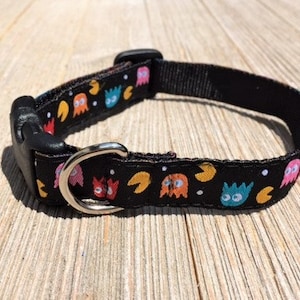 May include: Black dog collar with a Pac-Man pattern featuring colorful ghosts and yellow Pac-Man symbols.