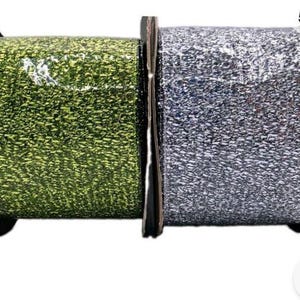 May include: Two spools of metallic ribbon are positioned side by side. The left spool features a vibrant, shimmering green textured ribbon, while the right spool displays a bright, reflective silver textured ribbon on a black core.
