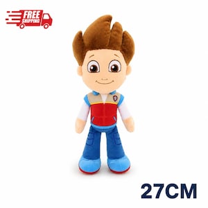 May include: A plush toy of a cartoon character with brown hair, wearing a red and beige vest over a white long-sleeved shirt, blue pants, and blue shoes. The character has large brown eyes and a small smile. The figure measures 27 cm in height.