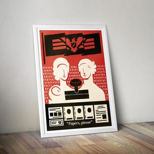 May include: A framed poster featuring a red background with two stylized white figures, a black stamp, and a black flag with an eagle emblem. The bottom section displays black and white document icons and the text "Papers, please" in white lettering.