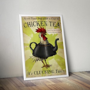 Op de afbeelding: Een ingelijste poster met een haan die uit een zwarte theepot komt. De tekst luidt: Start Your Day with a Cup of CHICKEN TEA, Only the Best will Cock-a-Doodle-Doo! en It's CLUCKING Tasty! De achtergrond heeft een lichtgroen zonnestraalpatroon.