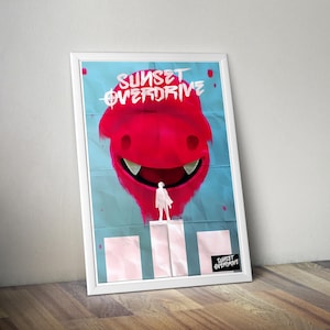 May include: A framed poster featuring a large red monster head with sharp teeth against a light blue background. Below the monster, a white silhouette of a person stands on a white block. The text SUNSET OVERDRIVE appears at the top and bottom.