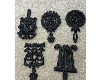 Set van 5 vintage gietijzeren onderzetters van Wilton Company, functioneel en decoratief.