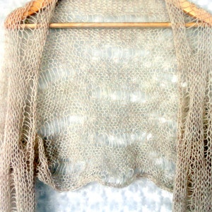 Bohemian-style light beige shrug with extra-long bell sleeves and a cropped fit. Crafted with breathable mohair-acrylic yarn, it adds texture and movement to your outfit. A whimsical choice for those who love handmade and slow fashion.