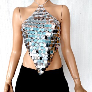 This silver halter top is hand-crocheted with oversized mirror sequins that shimmer and move with light. The shape flatters with a pointed front and tie-up neck, ideal for styling with skirts or wide-leg pants for a festival, club, or New Year’s Eve look.