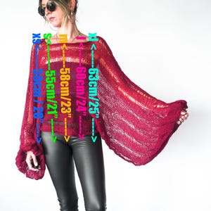a red open-knit sweater with bell sleeves. Measurements are indicated on the garment: 20" to 25" sleeve length, 23" to 24" width. The sweater is a deep red color and has a loose, flowing design.