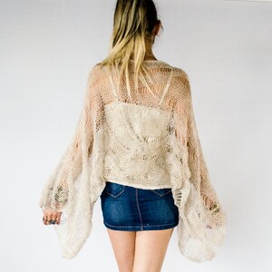 Cropped mohair shrug in neutral ecru beige with a see-through texture and romantic wide sleeves. Ideal for layering over tank tops and dresses. This open-knit piece suits fairycore, cottagecore, and summer festival aesthetics.