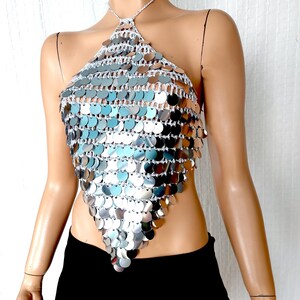 Reflective sequin halter top made from crochet and oversized silver discs. Its glimmering surface and plunging triangular silhouette make it the perfect statement piece for glam events, beach parties, or eye-catching stagewear.