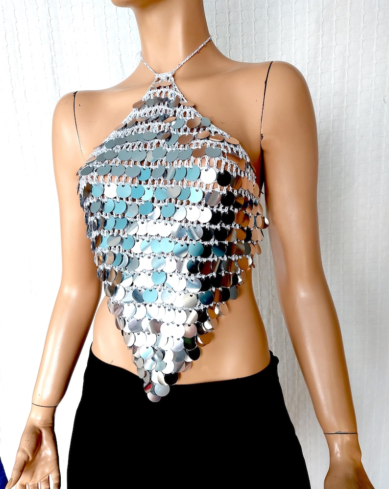 Reflective sequin halter top made from crochet and oversized silver discs. Its glimmering surface and plunging triangular silhouette make it the perfect statement piece for glam events, beach parties, or eye-catching stagewear.