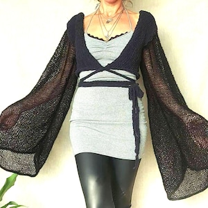 May include: Black crochet top with long, wide sleeves and a wrap-style neckline. The top is made of a lightweight, open-weave fabric.