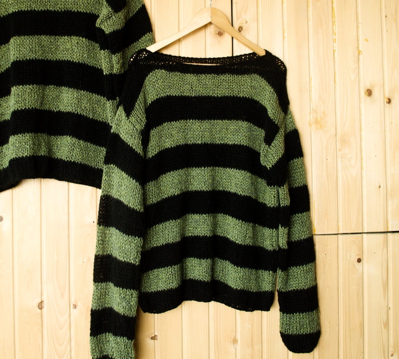 Grunge aesthetic striped mohair sweater in black and faded green, designed with a wide neckline and relaxed sleeves for a casual, edgy outfit.