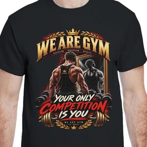Könnte beinhalten: Ein schwarzes T-Shirt mit kurzen Ärmeln und einem Grafikdruck einer muskulösen Person vor einem Spiegel. Der Text lautet WE ARE GYM und YOUR ONLY COMPETITION IS YOU, ergänzt durch Illustrationen von Hanteln, einer goldenen Krone und Lorbeerkränzen.