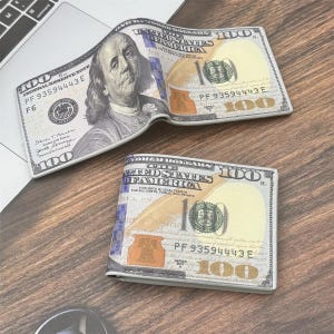 May include: A bi-fold wallet featuring a realistic print of a United States one hundred dollar bill. The exterior displays the portrait of Benjamin Franklin, the number 100, and the text United States of America, with a white and gold color scheme.