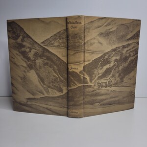 May include: A vintage book with a sepia-toned illustration of a mountain landscape and a horse-drawn wagon. The book's spine displays the title "Whistlers' Van" and the author's name, "Jones." The publisher's name, "Viking," is also visible.
