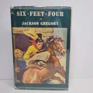 May include: A vintage paperback book cover with a green background. The title "SIX FEET FOUR" is printed in white with a star between the words. The author "JACKSON GREGORY" is printed in white below the title. The cover features an illustration of a man on horseback riding through a doorway.