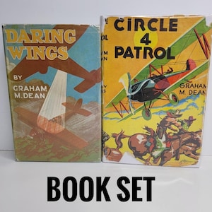 Può includere: Due libri vintage con copertina rigida intitolati Daring Wings e Circle 4 Patrol di Graham M. Dean. La copertina di Daring Wings mostra un aereo marrone in un cielo blu. La copertina di Circle 4 Patrol raffigura un biplano verde e un cavallo.