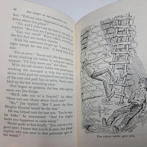 May include: An open book with text and a black and white illustration. The illustration depicts a person falling from a wooden ladder, with another person looking on. The text on the page is from a story titled "The Secret of the Forgotten City."