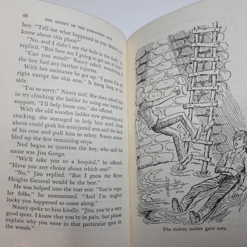 May include: An open book with text and a black and white illustration. The illustration depicts a person falling from a wooden ladder, with another person looking on. The text on the page is from a story titled "The Secret of the Forgotten City."