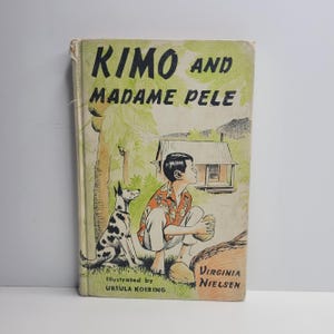 May include: Vintage book cover titled "Kimo and Madame Pele." The cover features an illustration of a boy, a Dalmatian dog, and a small house. The boy is wearing a patterned shirt and white pants. The book's title is in large, green letters.