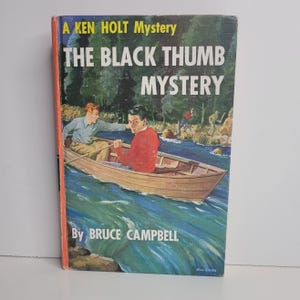 May include: Vintage hardcover book titled "The Black Thumb Mystery" by Bruce Campbell. The cover features an illustration of two young men in a rowboat on a river, with other figures in the background. The book has a red and orange spine.