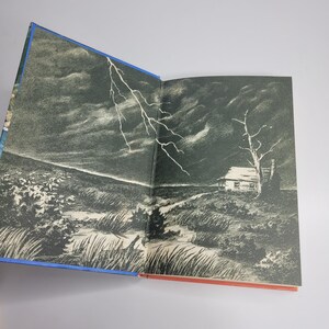 May include: Open book illustration featuring a dramatic, stormy landscape. A white lightning bolt streaks across a dark, cloudy sky. A small house and a bare tree are visible on a grassy hill. The book's edges are blue and red.