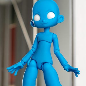 May include: A bright blue articulated doll figure with a smooth, matte finish. The figure features a rounded head, large blank white eyes, and a small nose and mouth. It has jointed shoulders, elbows, wrists, hips, and knees for posing.