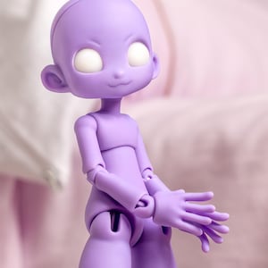 May include: A ball-jointed doll with smooth, light purple skin, a rounded head, and large, blank white eyes. The figure features articulated joints at the shoulders, elbows, and wrists, with hands positioned together in front of the torso.