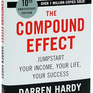 May include: A white book titled The Compound Effect by Darren Hardy, 10th Anniversary Edition. The cover features red and black text, a light blue circle badge, and a quote by David Bach stating over 1 million copies sold.