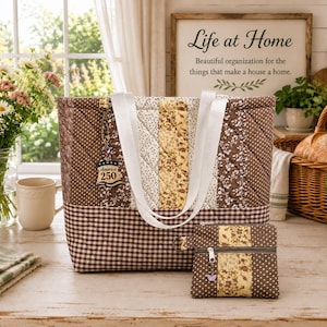 May include: A quilted tote bag and a matching small zippered pouch featuring a brown and white gingham base, brown polka dot panels, and a central yellow floral strip. The tote has white fabric straps and a hanging tag that reads America 250.