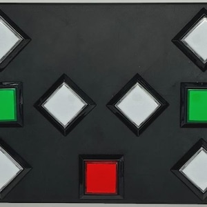 May include: A rectangular black control panel featuring a grid of buttons. The layout includes six white diamond-shaped buttons, two square green buttons, and one square red button, all set within a flat, dark, matte-finished plastic housing.
