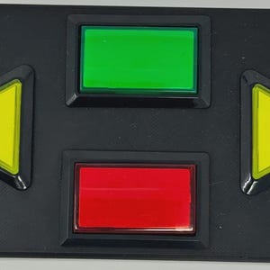 May include: A rectangular black control panel featuring four buttons. Two yellow triangular buttons point left and right on the sides. A green rectangular button is positioned at the top centre, and a red rectangular button is at the bottom centre.