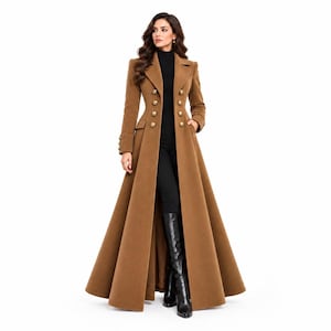 May include: A floor-length camel brown wool coat featuring a double-breasted front with two columns of gold-toned buttons, a structured collar, long sleeves, and two side pockets. The coat is worn over a black mock-neck top and black leggings.