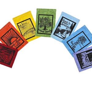 May include: A set of eight colorful fabric flags with positive messages printed on them. The flags are arranged in a semi-circle, with the red flag at the bottom and the purple flag at the top. The messages on the flags include "be kind", "seek & share truth", "compassionate", "celebrate diversity", "stand for justice & democracy", "find joy & peace", "help each other", and "be courageous".