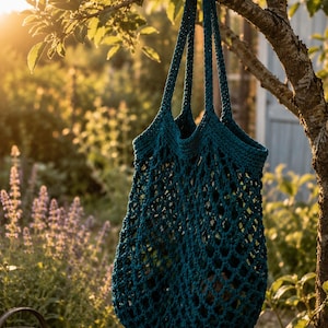 May include: A deep teal crochet market bag featuring an open net pattern and two long shoulder straps. The bag is constructed with a solid crocheted top border and a continuous mesh body, showcasing a consistent dark blue-green yarn texture.